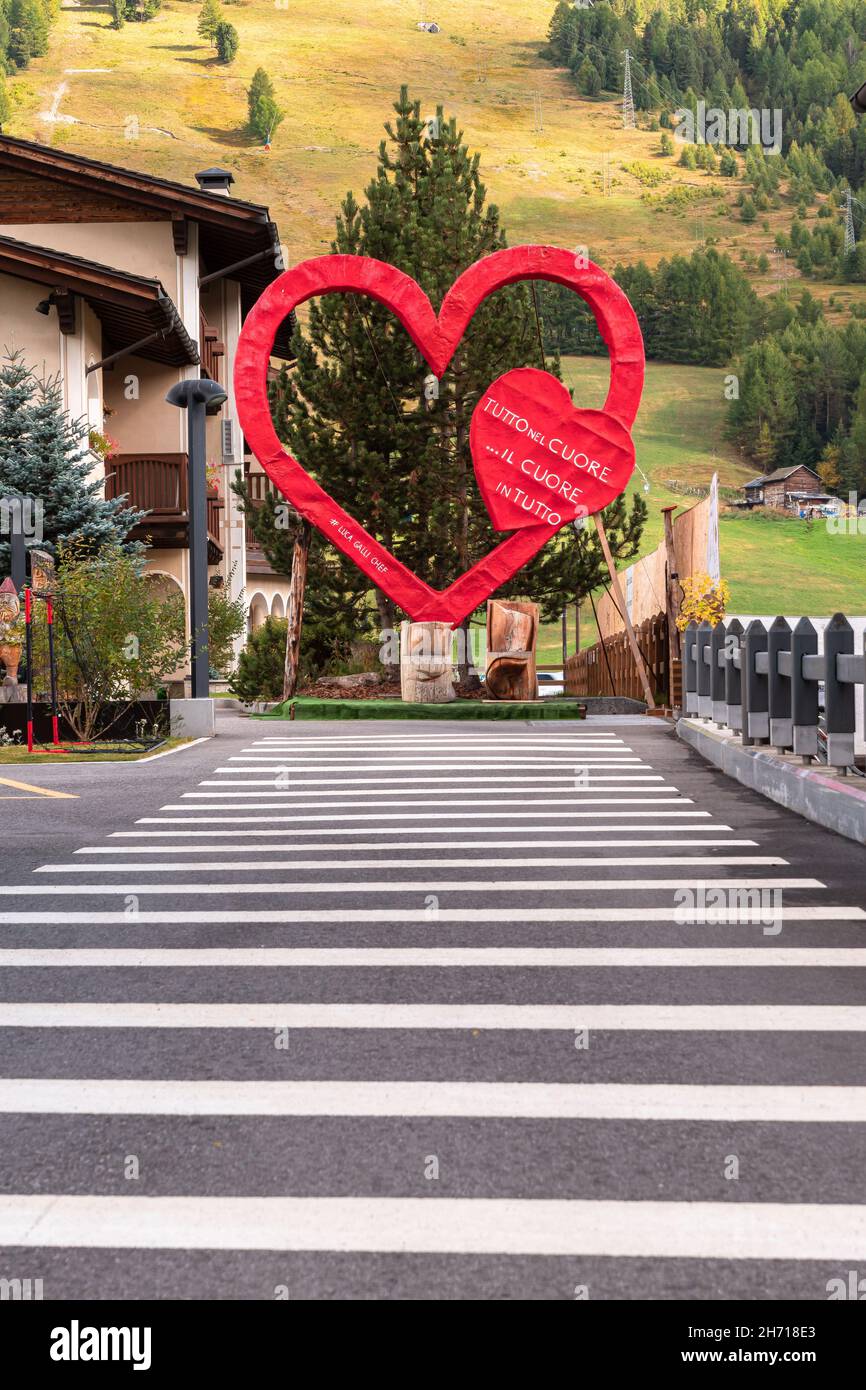 Livigno, Italien - 29. September 2021: Ein großes künstliches rotes Herz mit einer Inschrift in der folgenden englischen Übersetzung: Alles ist im Herzen... eine hea Stockfoto