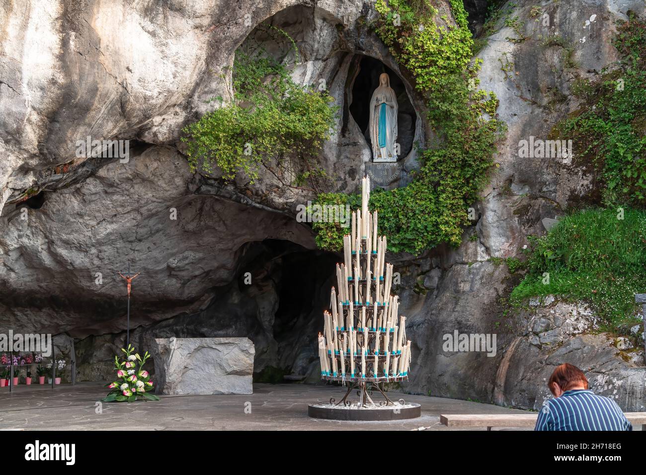 Lourdes, Frankreich - 28. August 2021: Frau, die vor der Höhle der Erscheinungen der heiligen Maria in Lourdes betet Stockfoto