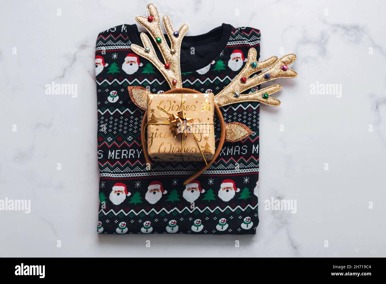 Frohe Weihnachten. Draufsicht auf weihnachts-Pullover mit hellen weihnachts-Spielzeug Hirschgeweih auf einem Marmortisch.Weihnachtskonzept Hintergrund Stockfoto