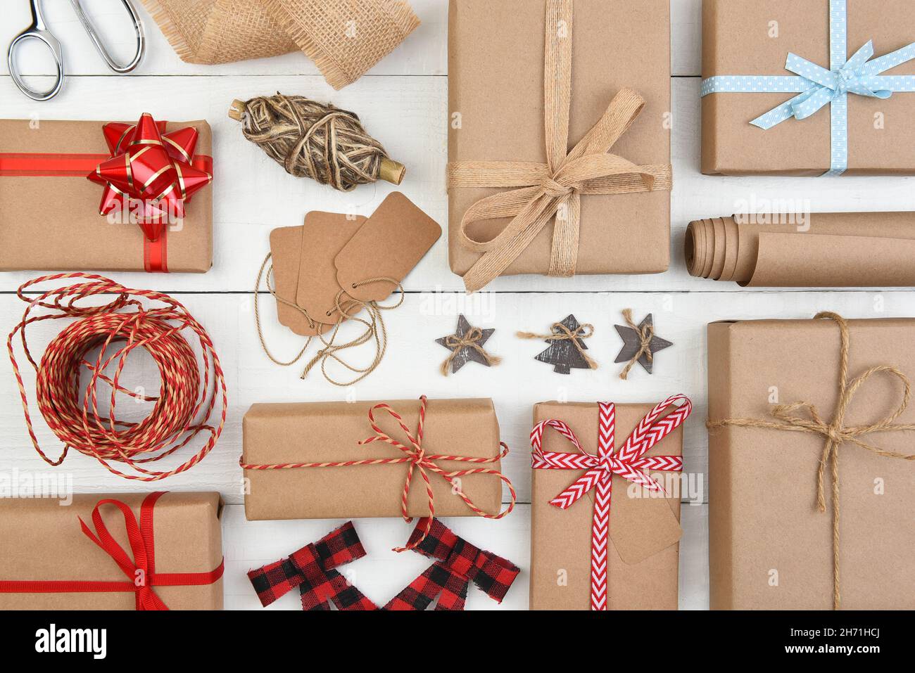 Christmas Flat Lay - Einfarbig braunes Kraftpapier verpackt Geschenke mit Zubehör füllen den gesamten Rahmen. Stockfoto