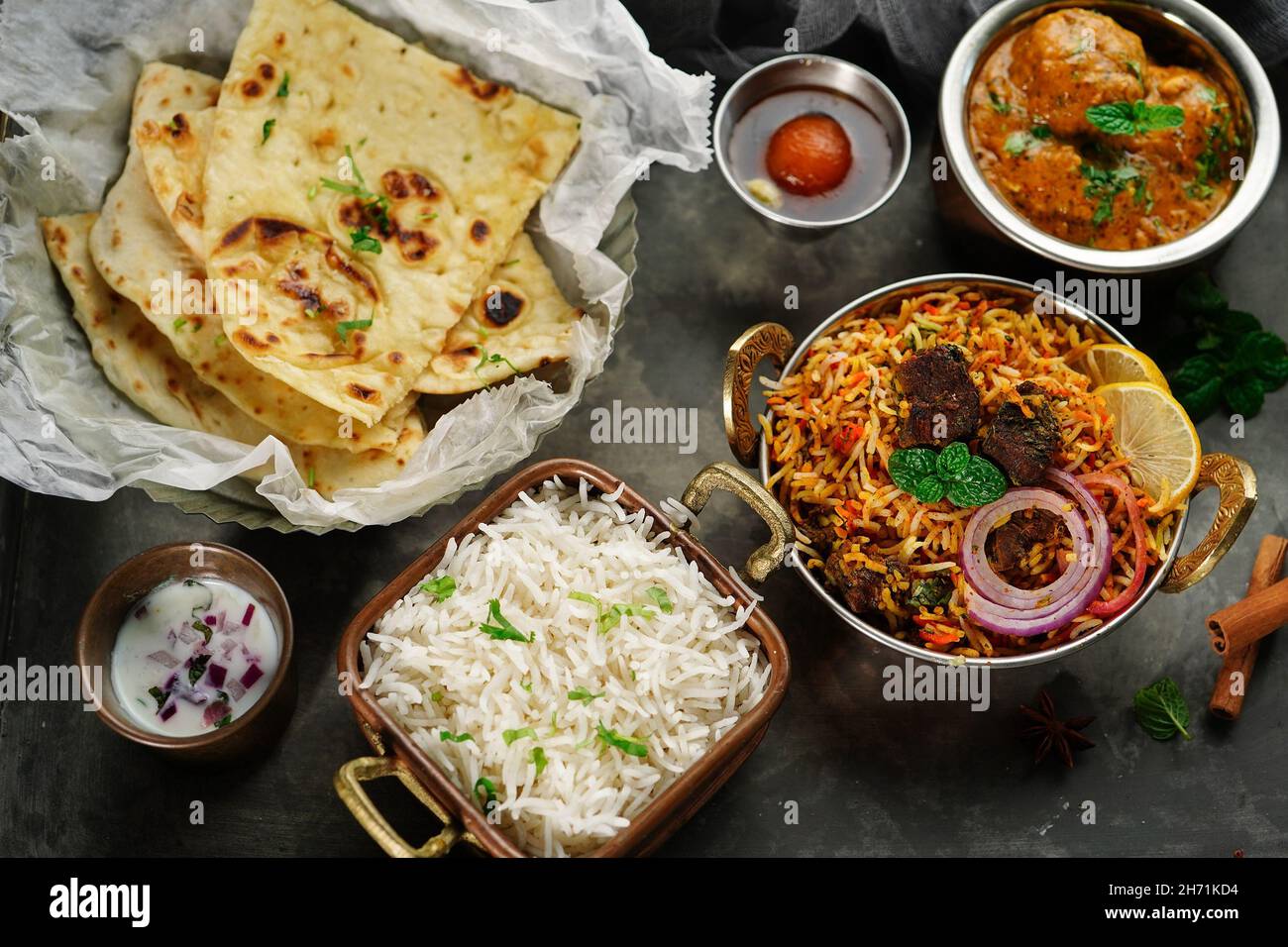 Indische Mahlzeit Thali - Hammelfleisch Biryani, Raita, Malai Kofta, Basmati-Reis, Butter Naan und Gulab Jamun auf einem Tablett serviert Stockfoto