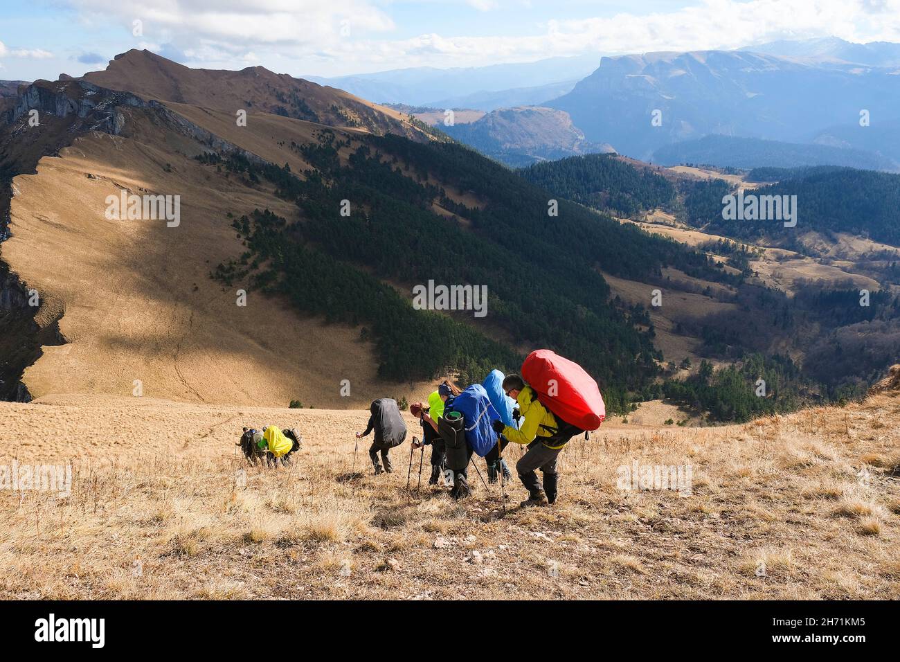 Gruppe von Reisenden mit großen Rucksäcken auf den Bergen. Rückansicht. Stockfoto