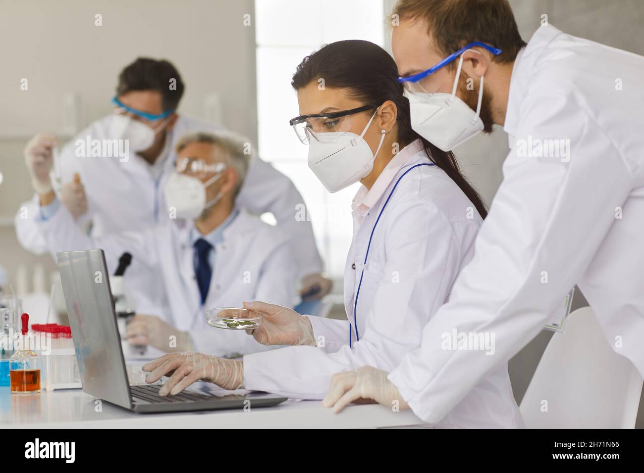 Wissenschaftler arbeiten zusammen, um Proben zu analysieren, während sie in einem modernen Forschungslabor arbeiten. Stockfoto