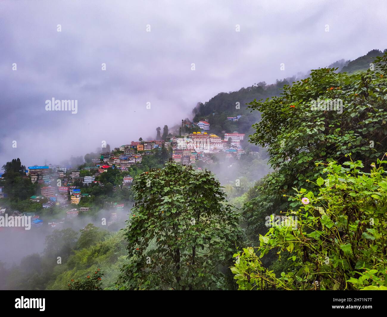 Die Stadt, die sich in einem Berghang mit dramatischem Himmel und Berghintergrund am Morgen befindet, wurde in darjeeling im Westen bengalindiens aufgenommen. Stockfoto