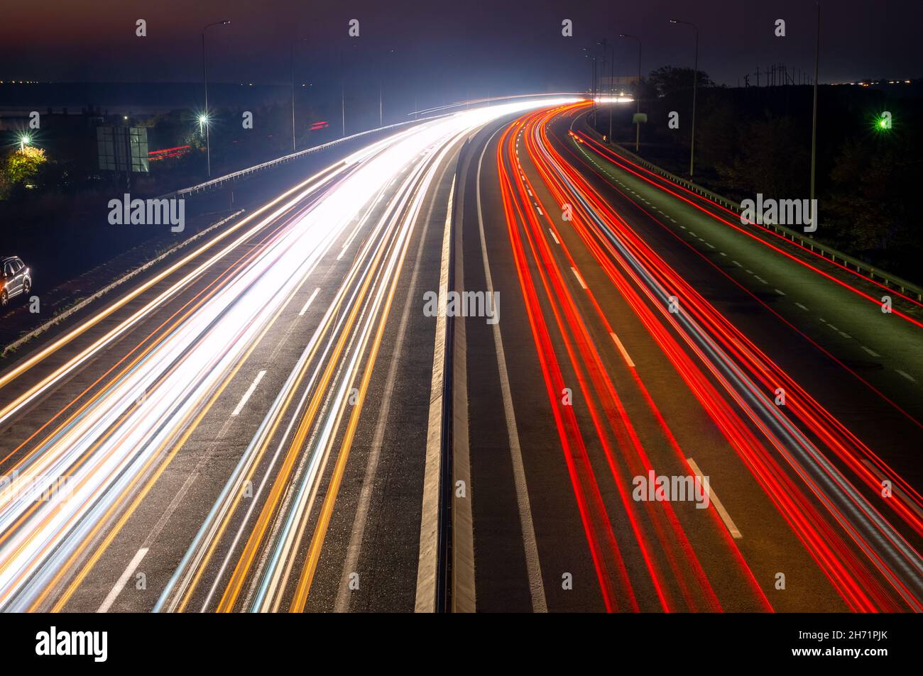 Schnellstraße in der Vorstadt bei Nacht. Spuren von Scheinwerfern und Schlussleuchten bei starkem Verkehr Stockfoto