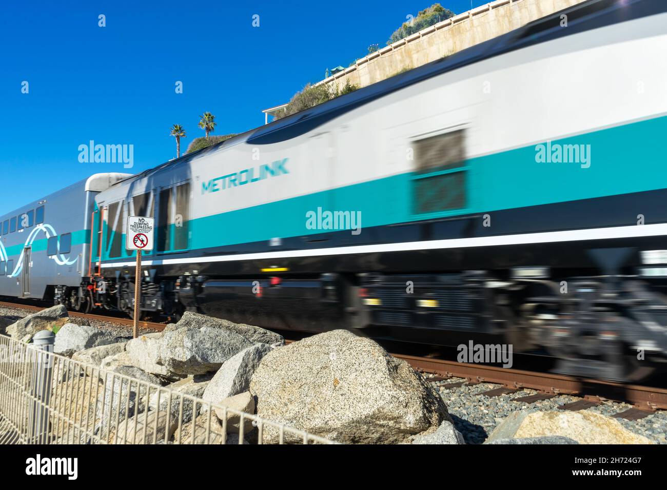 San Clemente, CA, USA – 13. November 2021: Der sich unscharf bewegende Metrolink-Nahverkehrszug fährt in San Clemente, Kalifornien, an einem No Trespassing-Schild vorbei. Stockfoto