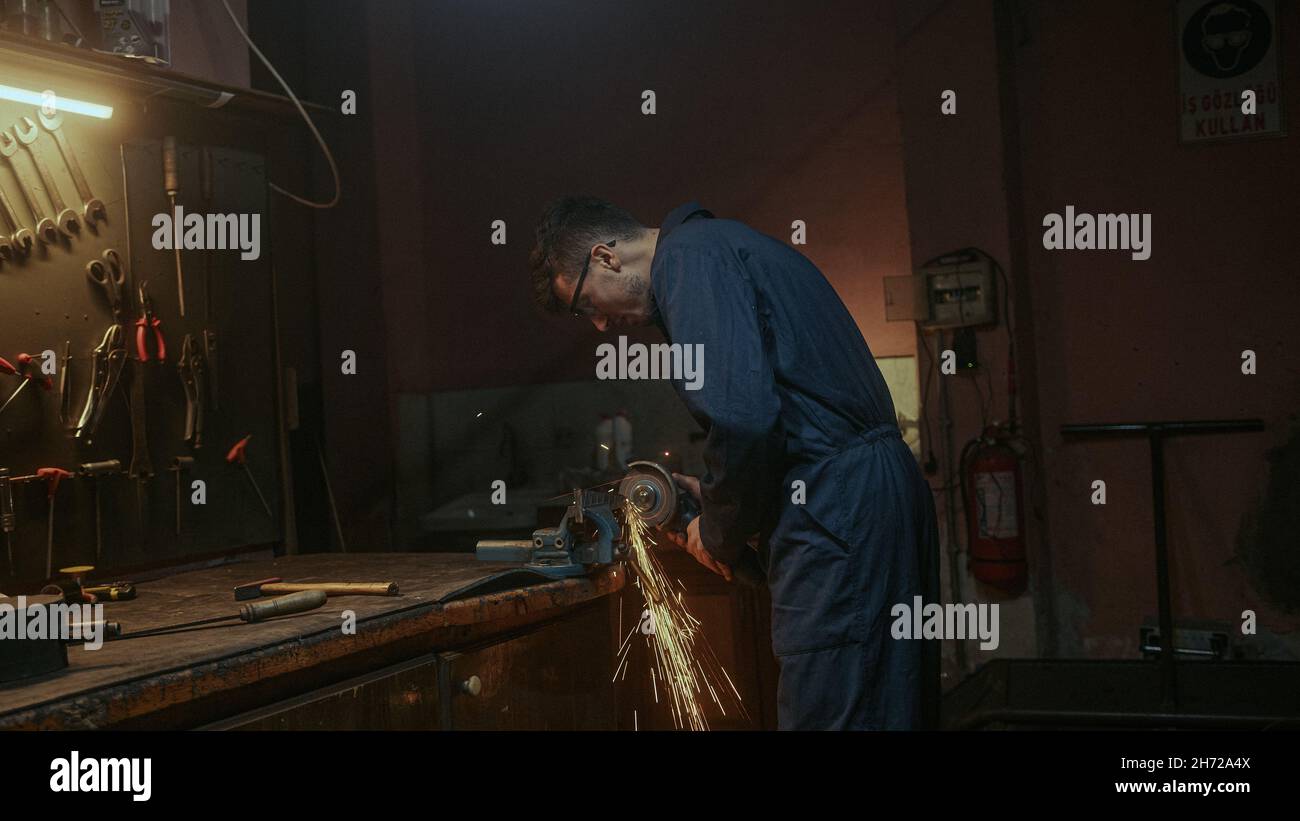 Junge Schmied Mann verwenden Eisen oder Metall Schneidemaschine und er Metallschleifen auf Stahl Ersatzteil in der Werkstatt Stockfoto