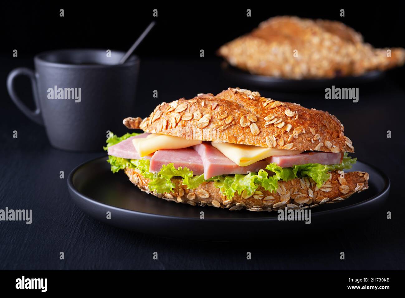 Croissant-Sandwich mit frischem Salat, Schinken und Frischkäse auf dunklem Hintergrund Stockfoto