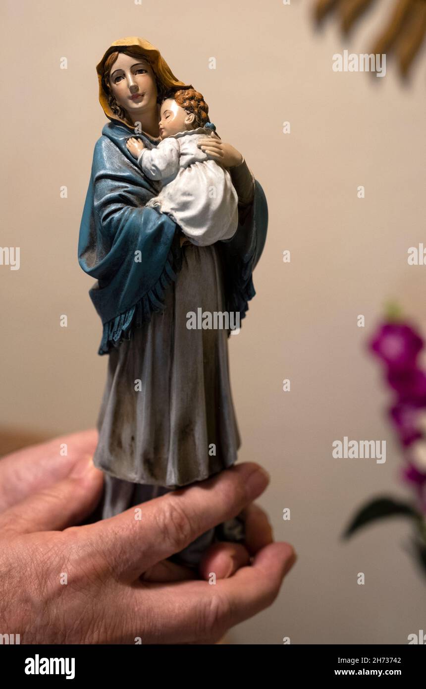 Nahaufnahme eines Mannes, der eine Statue von Maria und Jesus hält Stockfoto