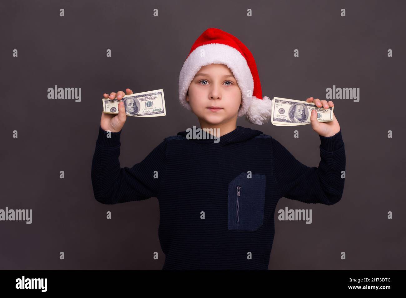 Der Junge hält zwei Dollarbündel in den Händen. Stockfoto