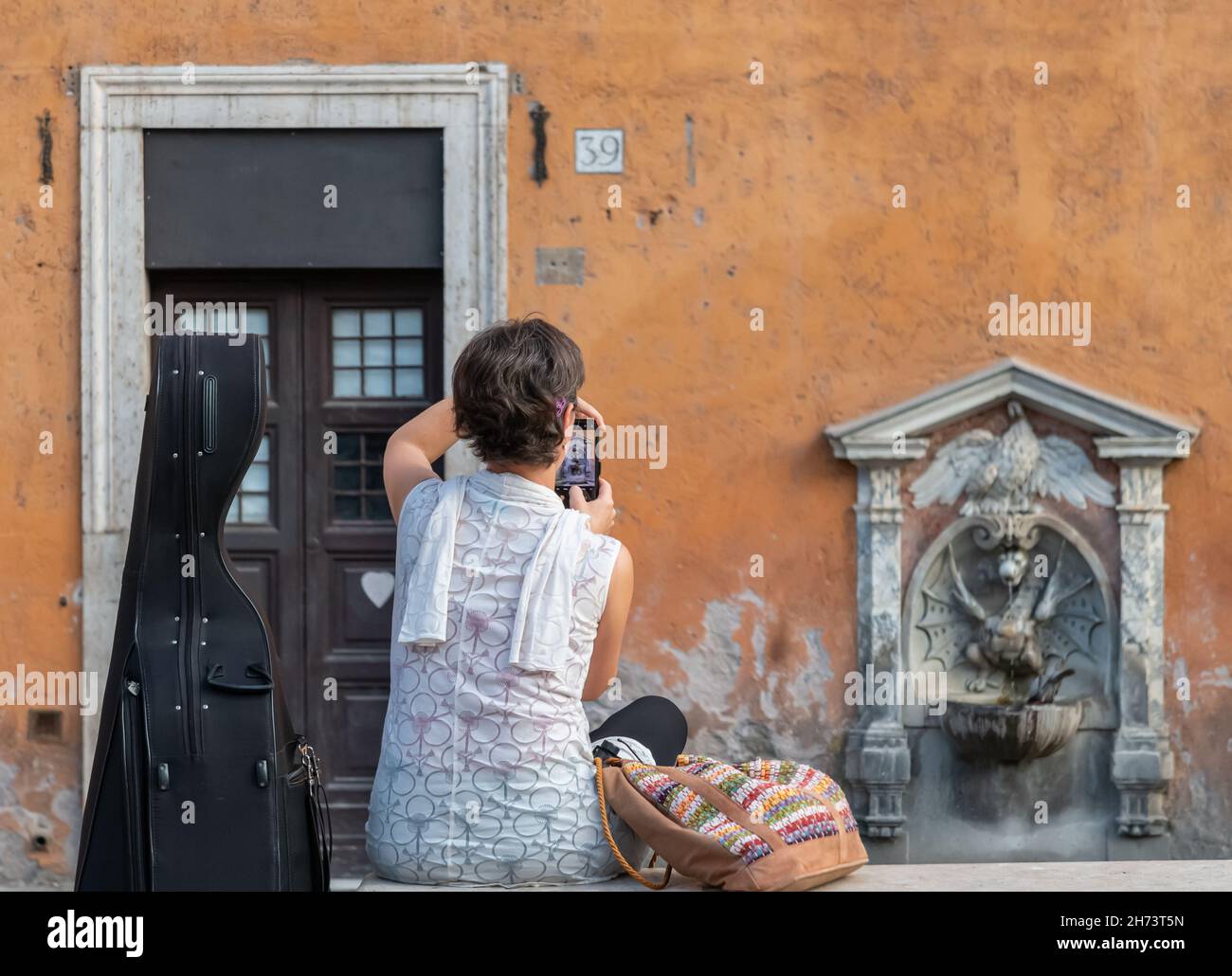Frau mit Cello macht foto von Italien historischer Trinkwasserbrunnen Kurdrache in der Nähe der Vatikanstadt Rom, Italien Stockfoto