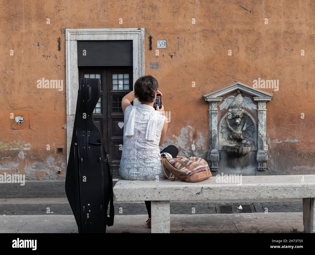 Frau mit Cello macht foto von Italien historischer Trinkwasserbrunnen Kurdrache in der Nähe der Vatikanstadt Rom, Italien Stockfoto