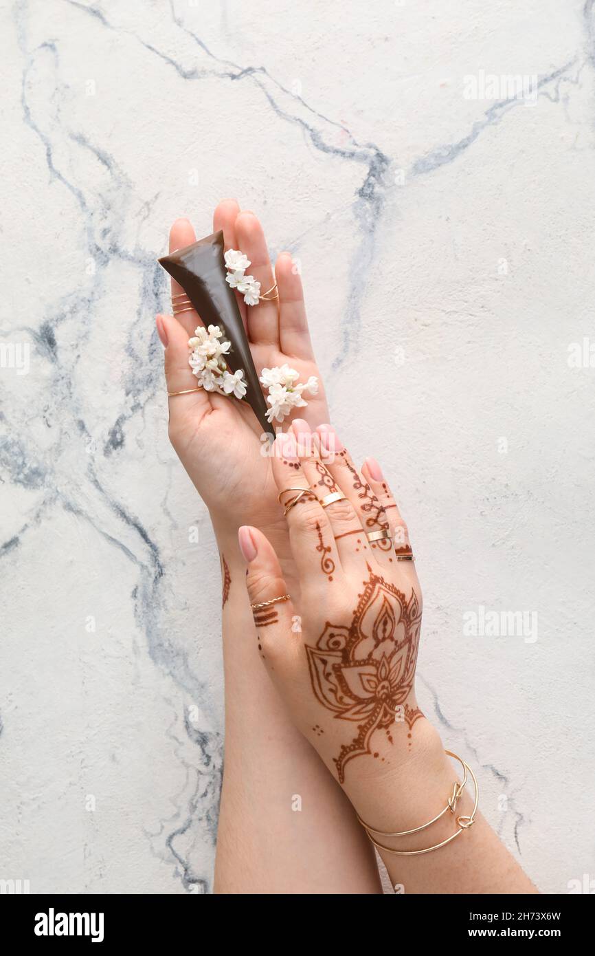 Henna bemalte weibliche Hände mit Farbe auf hellem Marmorhintergrund Stockfoto