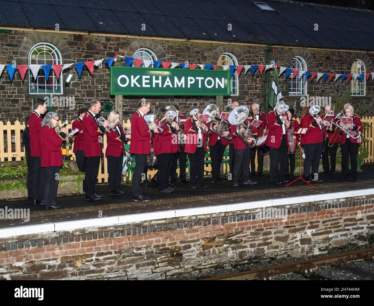 Samstag, 20. November 2021 - die Hatherleigh Silver Band tritt auf der Okehampton Station auf, um den ersten Zug der Dartmoor Line zu begrüßen. Nach fast 50 Jahren wurde ein regelmäßiger Passagierdienst nach Exeter eröffnet. Um den Weg zu erneuern, wurden 11 Meilen neuer Gleise mit 24.000 Betonballen und 29.000 Tonnen Ballast verlegt. Durch die Wiederherstellung des regulären Dienstes werden die Verbindungen für Pendler verbessert und Besuchern ein Terminal zur Erkundung des Dartmoor-Nationalparks zur Verfügung gestellt. Es wird die lokalen Unternehmen und den Tourismussektor stärken und den Einheimischen einen besseren Zugang zu Arbeit und Bildung ermöglichen. Stockfoto