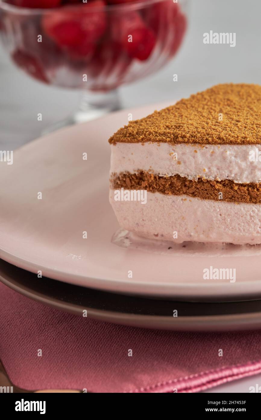 Vertikale Aufnahme eines No-Bake-Tortenstückes mit dreifacher Schokoladenmousse und einer Schüssel mit Erdbeeren Stockfoto