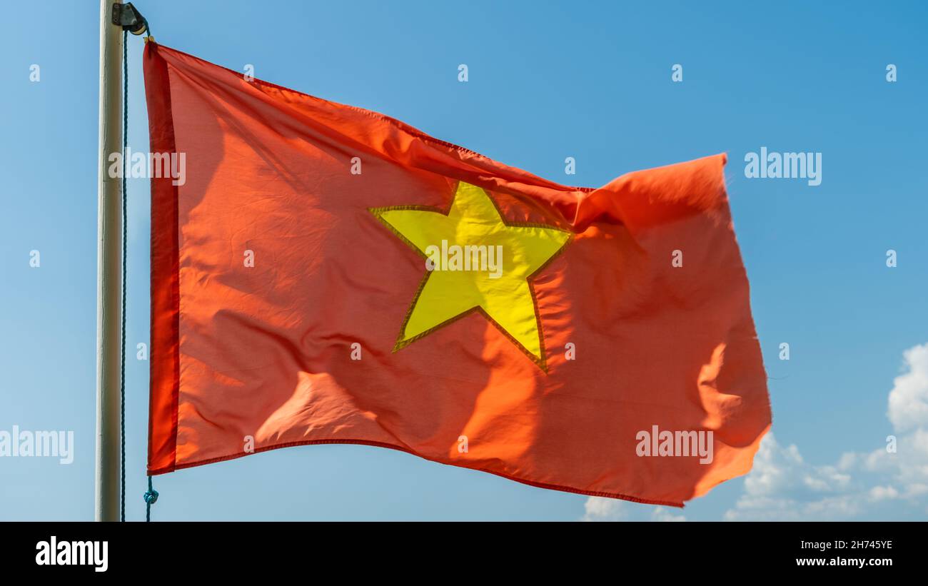 Nahaufnahme der roten Vietnam-Nationalflagge mit einem goldenen Stern in der Mitte, der am Himmel fliegt Stockfoto