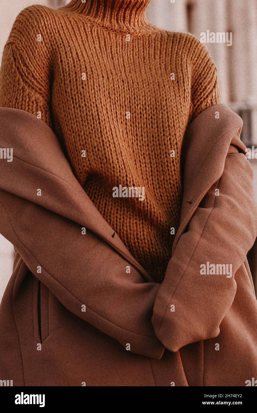 3/4-Frauenfigur in einem braunen, kuschelig warmen Mantel und orangefarbenem Strickpullover. Streetcasual Winter- oder Herbstmode. Stockfoto