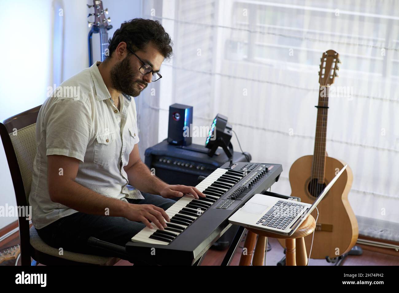 Musiker, der Klavier spielt, während er von seinem Heimstudio Aufnahmen Stockfoto