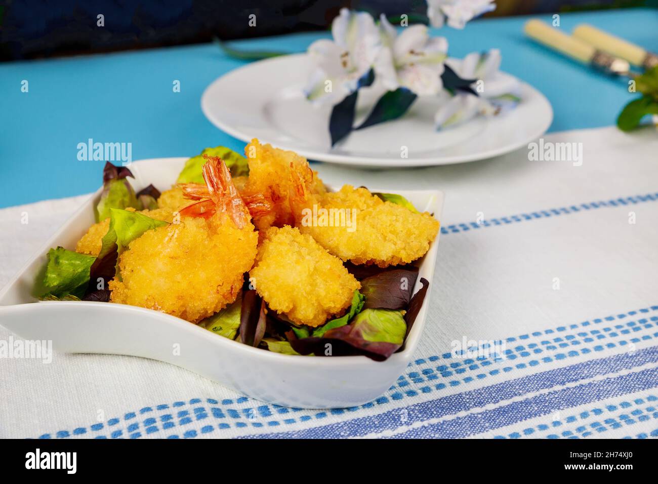 Frittierte panierte Garnelen mit grünem Salat und Tischset. Stockfoto