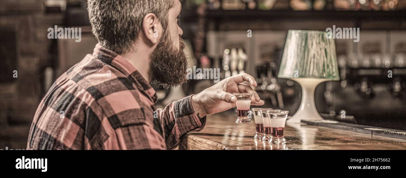 Trinken von Alkohol in Schnapsgläser in einem Nachtclub oder einer Bar. Bärtiger Mann Schüsse Cocktail. Tequila Shots, Wodka, Whisky, Rum. Barkeeper im Pub. Tequila-Schuss Stockfoto