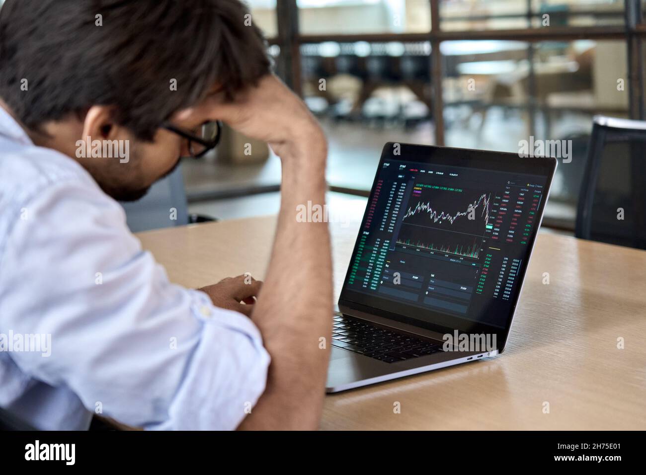 Gestresster Geschäftsmann, der den Handel an der Börse analysiert, fällt nach unten. Stockfoto