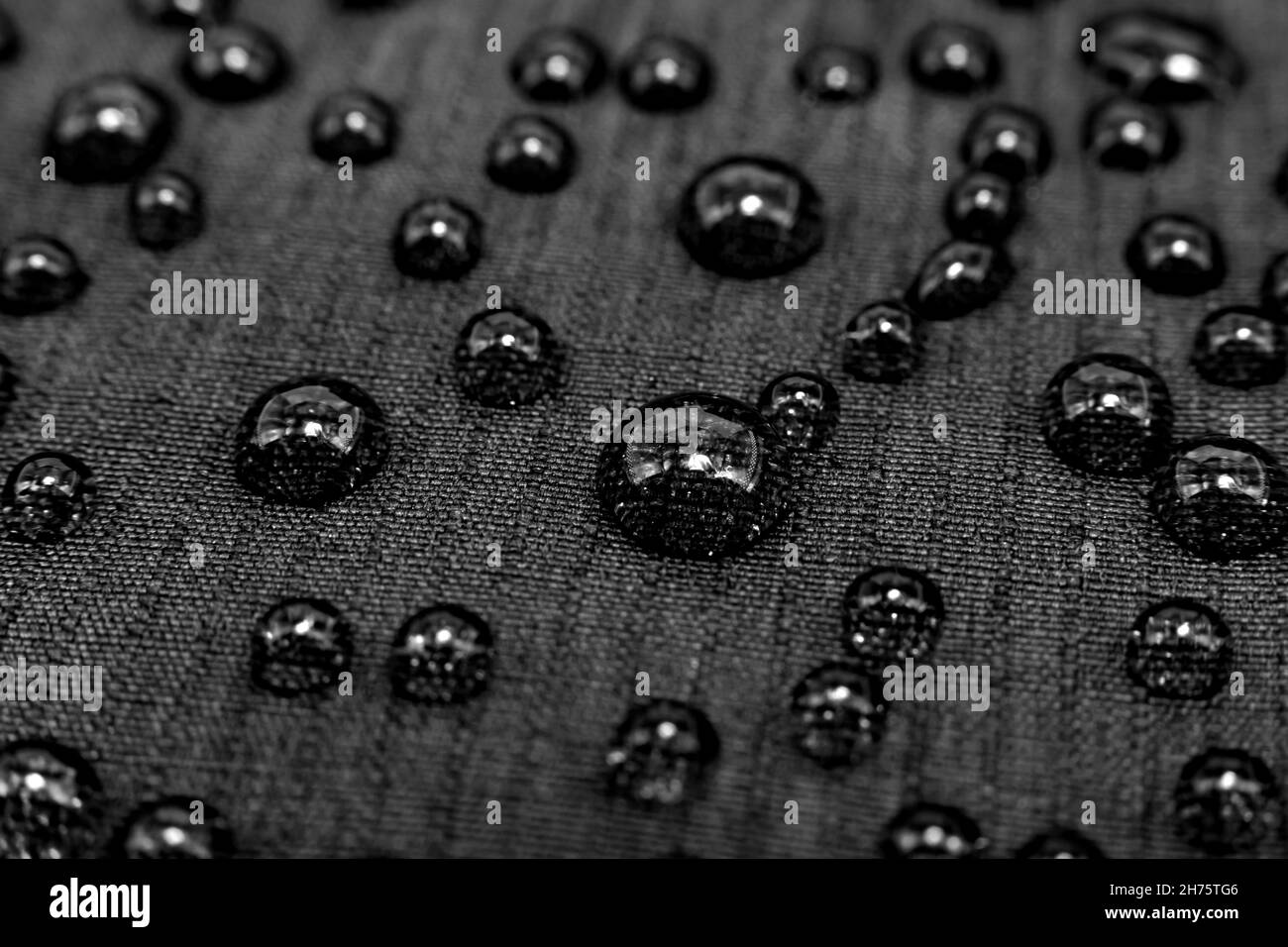 Wassertropfen auf der Oberfläche des wasserabweisenden Stoffes. Wasserdichtes Material Stockfoto