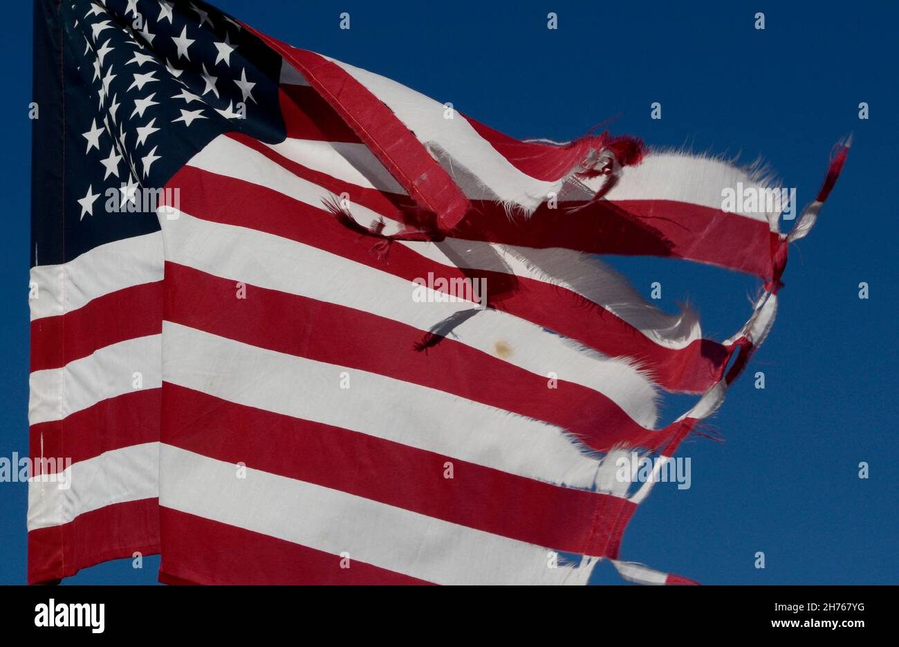 Auf einem Friedhof in Taos, New Mexico, fliegt eine zerschlagene amerikanische Flagge. Stockfoto