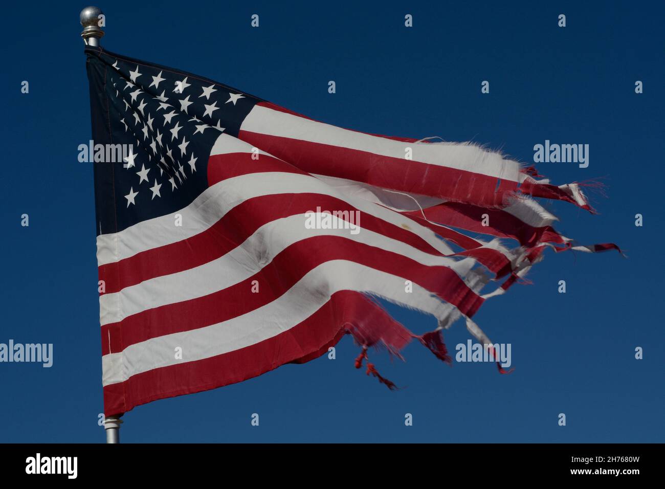 Auf einem Friedhof in Taos, New Mexico, fliegt eine zerschlagene amerikanische Flagge. Stockfoto