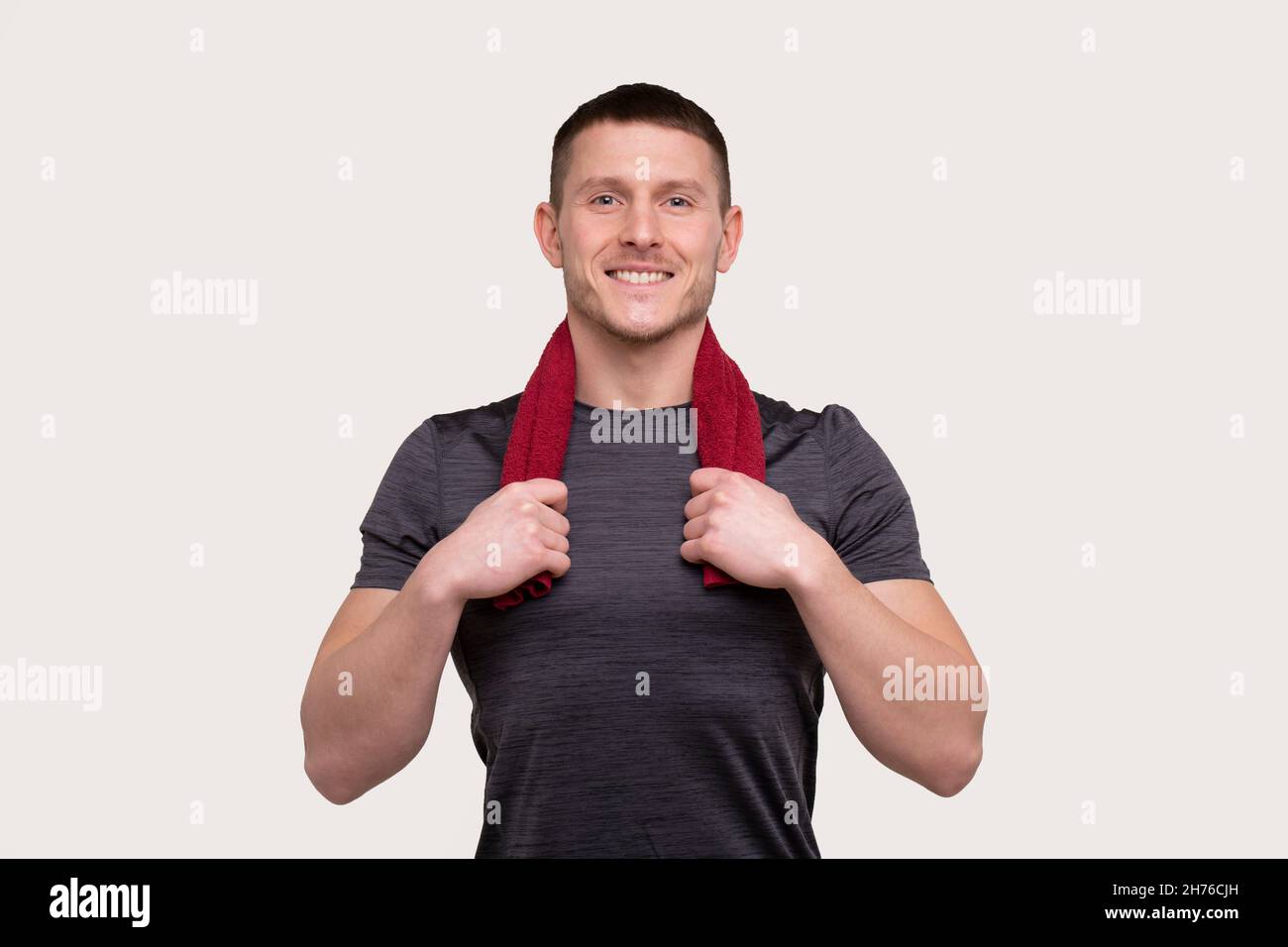 Mann, der mit Handtuch am Hals isoliert schmillt. Sportsman Portrait mit Handtuch in den Händen Stockfoto