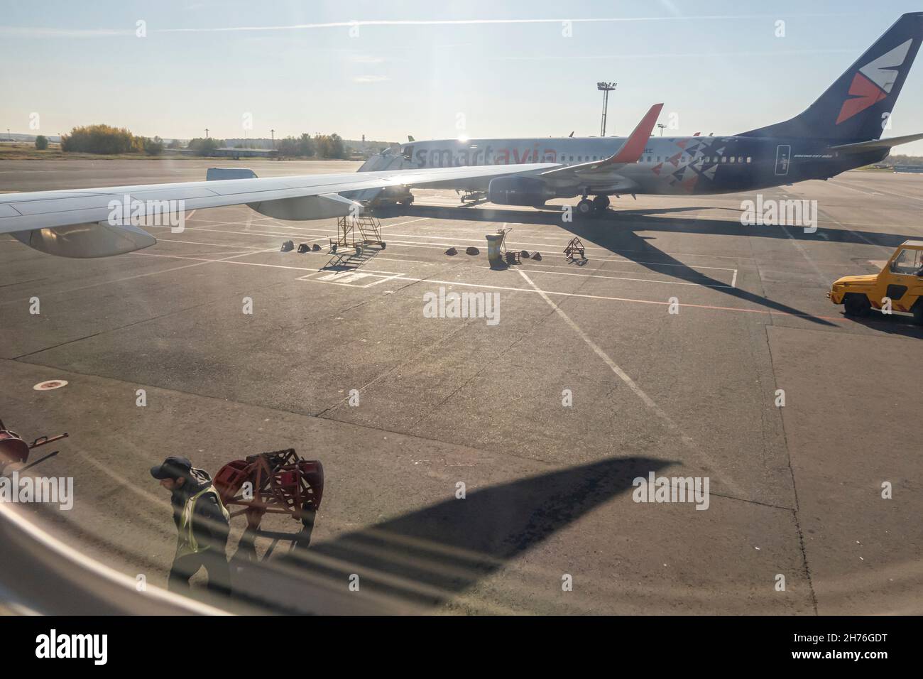 Blick auf einen Boeing 737-800-Flügel und einen Flugplatz durch das Flugzeugkabinenfenster am Mittag Stockfoto