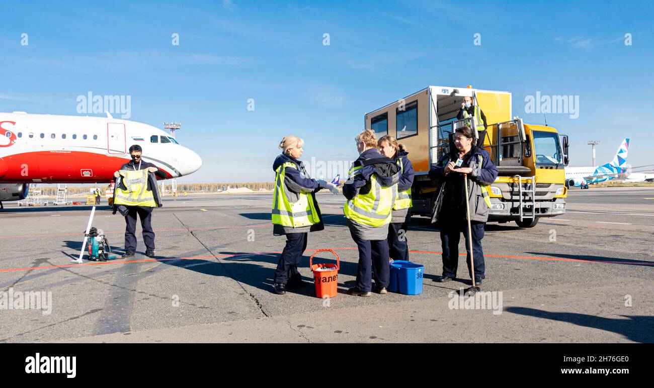 Reinigungspersonal in reflektierenden Jacken am Flughafen, DME, Moskau, Russland, macht Mittagspause von der Arbeit auf dem Asphalt des Flughafens Demodedovo Stockfoto