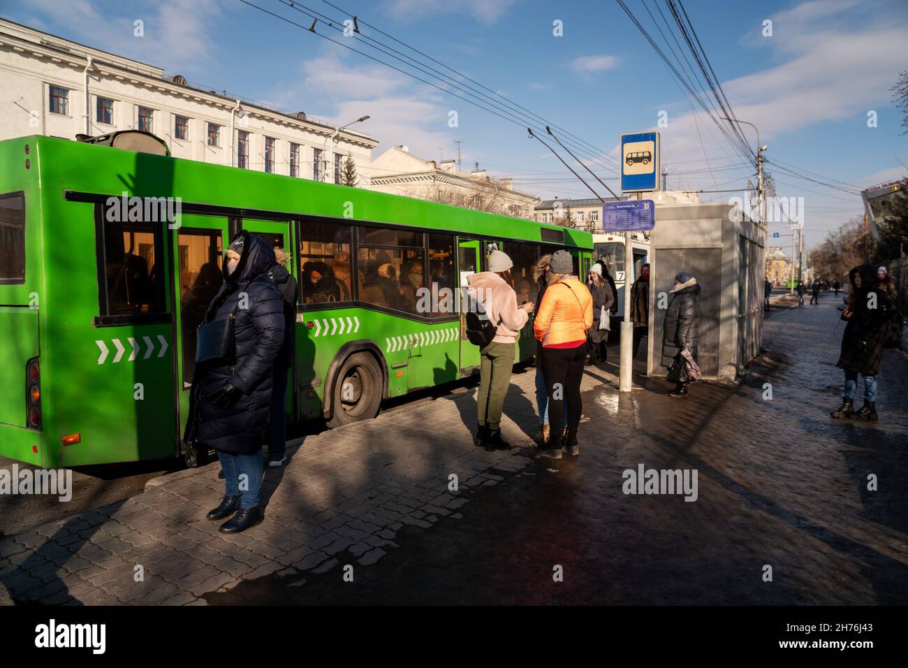 Bushaltestelle Kino Luch mit einem weißen Trolleybus und einem grünen Bus, der langsamer wird und an einem Frühlingstag auf dem Prospekt Mira wartet. Stockfoto