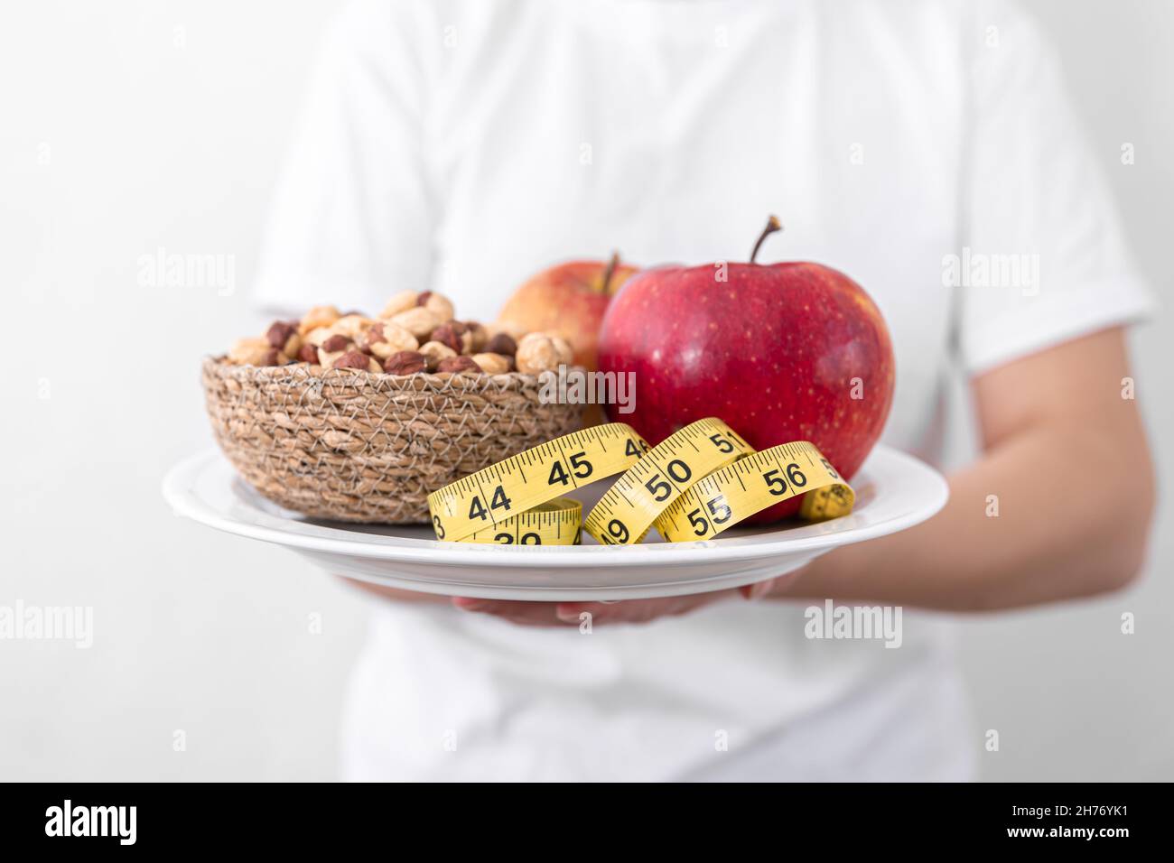 Teller mit Äpfeln, Nüssen und Maßband, Diät und gesunde Ernährung Konzept. Stockfoto