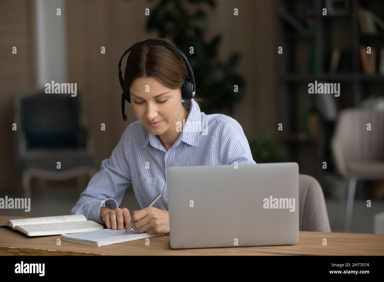 Aufmerksame Frau hören Audio-Kurs Notieren Studium verwenden moderne Technik Stockfoto