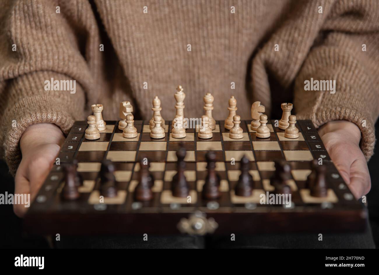 Schachbrett mit hölzernen Schachfiguren in weiblichen Händen. Stockfoto