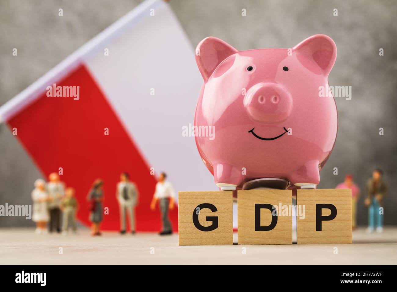 Sparschwein, Holzwürfel mit Text und Spielzeug Männer aus Kunststoff auf dem Hintergrund der Flagge, das Konzept zum Thema Polen BIP Stockfoto