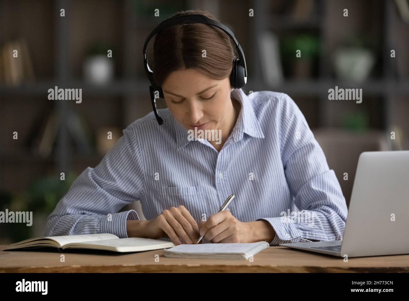 Frau trägt ein Headset und bemerkt, dass sie während des Studiums Videocall auf dem Laptop verwenden kann Stockfoto