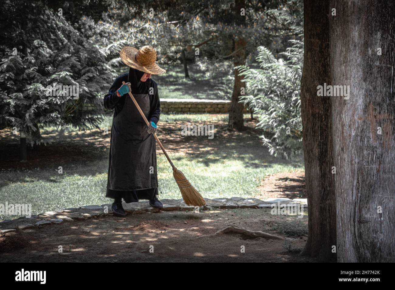 Fleißige Nonne fegt Blätter von der Terrasse im orthodoxen Bodbe Kloster, Georgien. Stockfoto