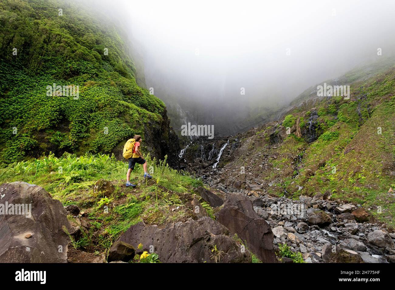 Junge mit Rucksack beim Wandern zum Wasserfall Ribeira grande. Flores, Azoren, Portugal Stockfoto