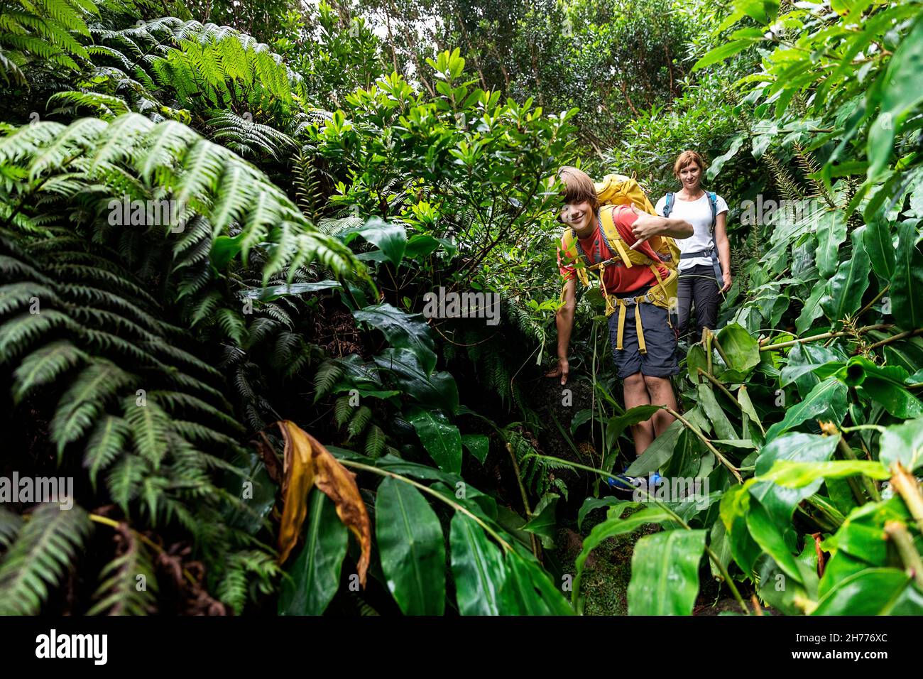 Mutter und Sohn wandern in dichter tropischer Vegetation auf dem Weg zum Wasserfall Cascata da Ribeira Grande, Flores Island, Azoren, Portugal Stockfoto