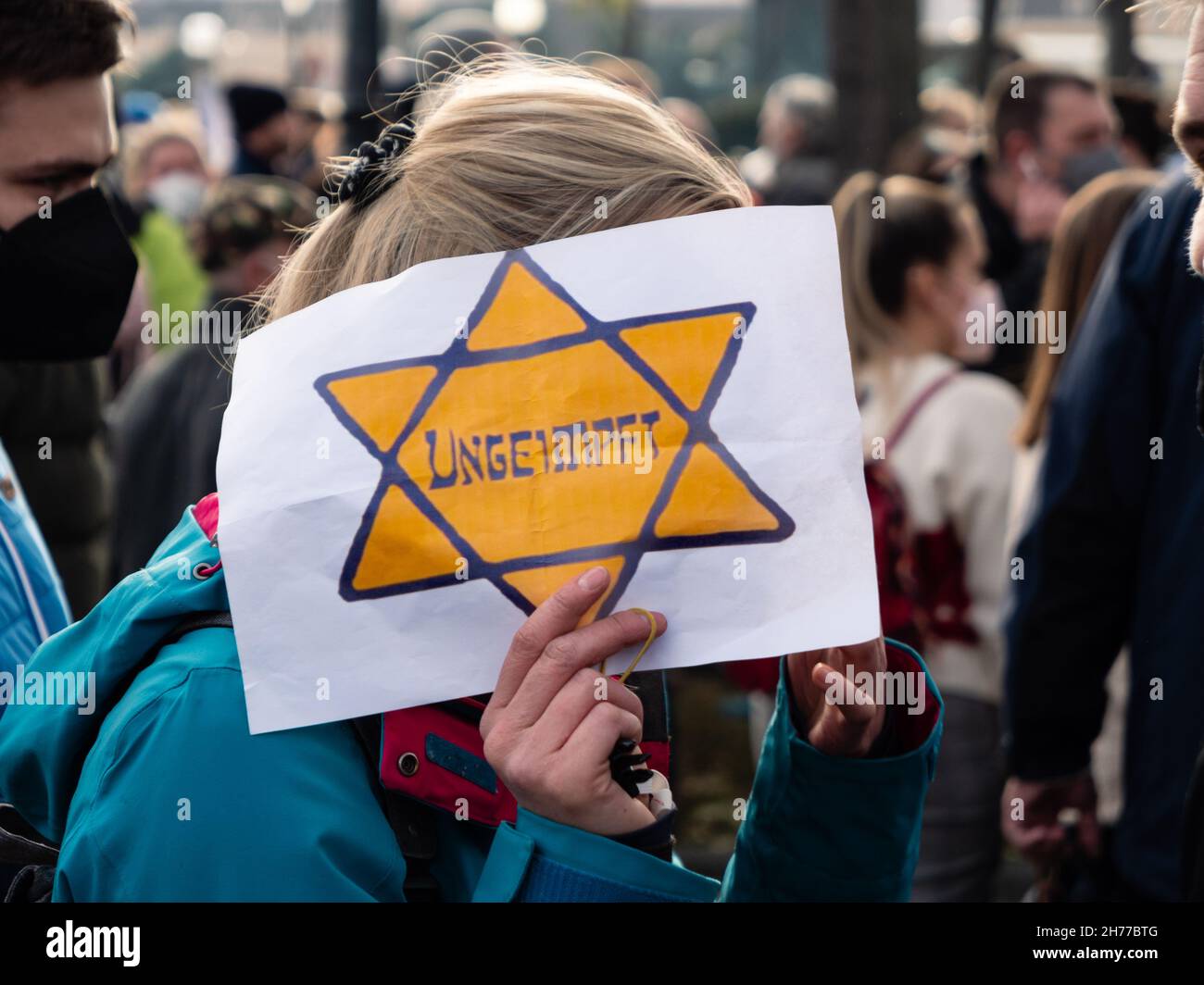 Wien, Österreich - November 20 2021: Anti-Vax Covid-19 Demonstrator Holdig Zeichen 'Ungeimpft' oder 'ungeimpft' in einem gelben Patch oder jüdischen Abzeichen Stern von Stockfoto