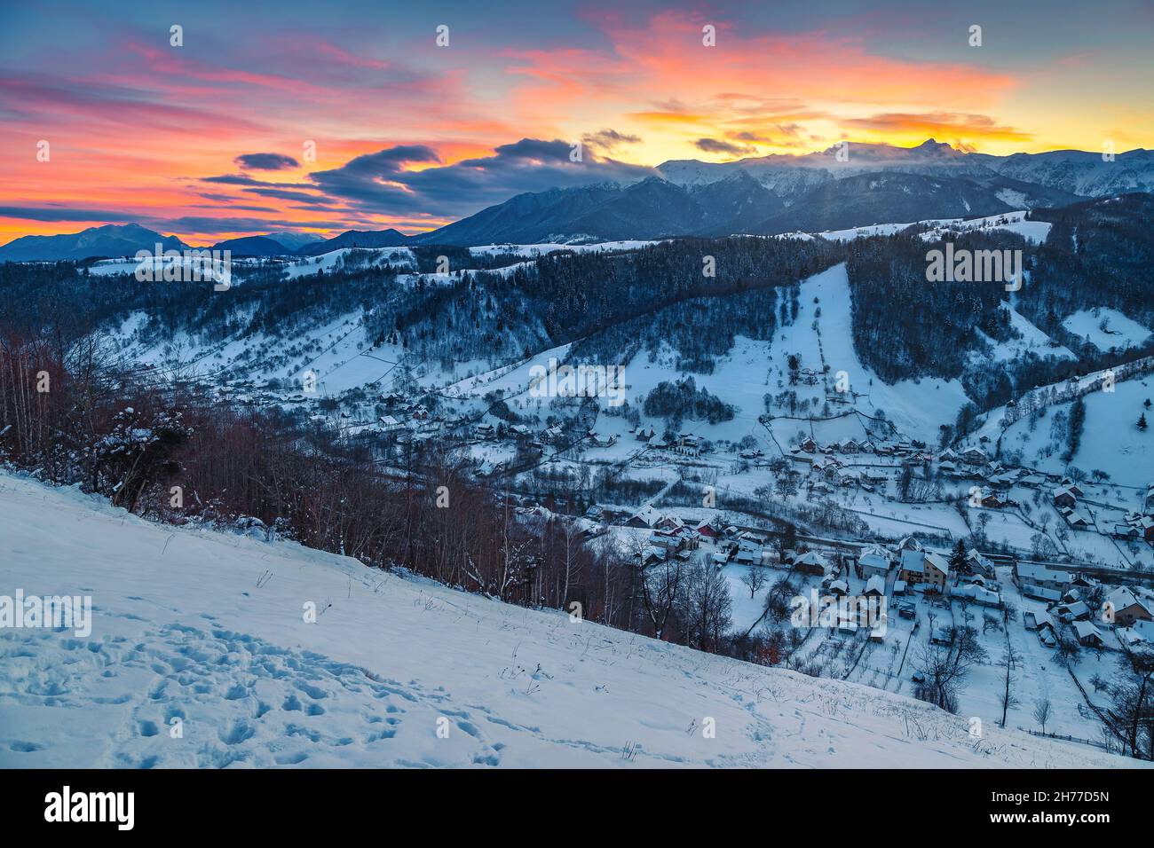 Erstaunliche Winter Dämmerung Landschaft mit verschneiten Bergen. Malerischer Sonnenaufgang und schneebedeckter Bergrücken im Hintergrund, Bucegi Berge, Karpaten, Rumänien, Stockfoto