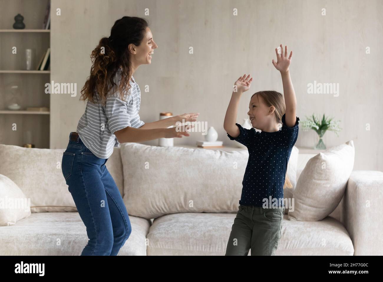 Lebhafte Frau und Tochter tanzen im gemütlichen Wohnzimmer Stockfoto