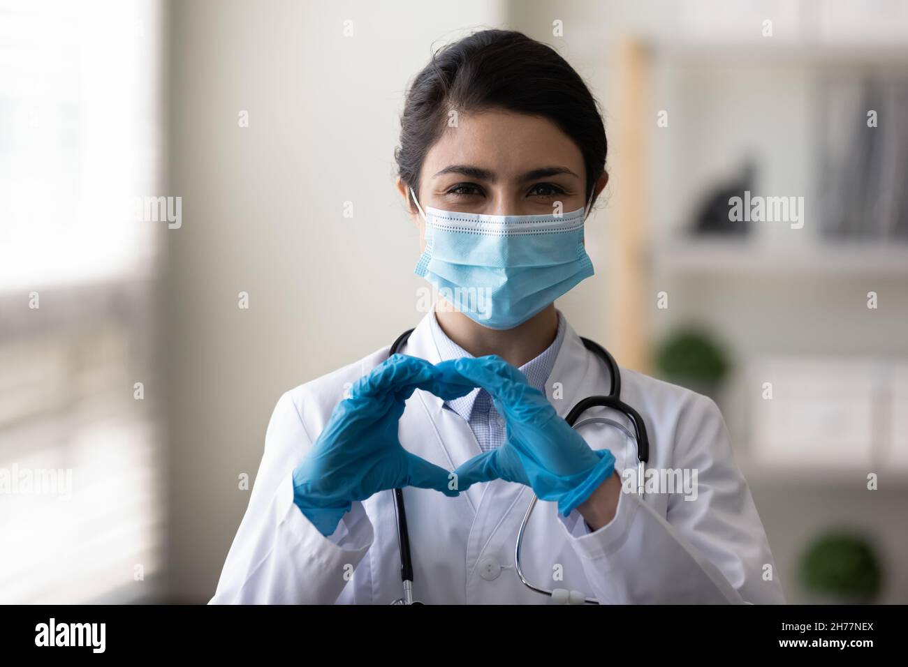 Kopf geschossen Porträt glücklich indisch Frau Arzt zeigt Herzgeste Stockfoto