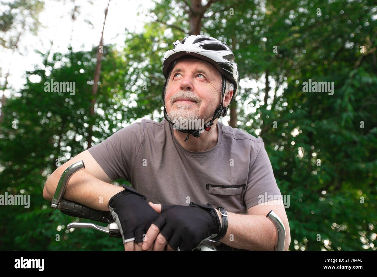 Älterer Mann auf dem Fahrrad während der schönen Sommerzeit im Wald, lächelnd, genießen Reise Stockfoto