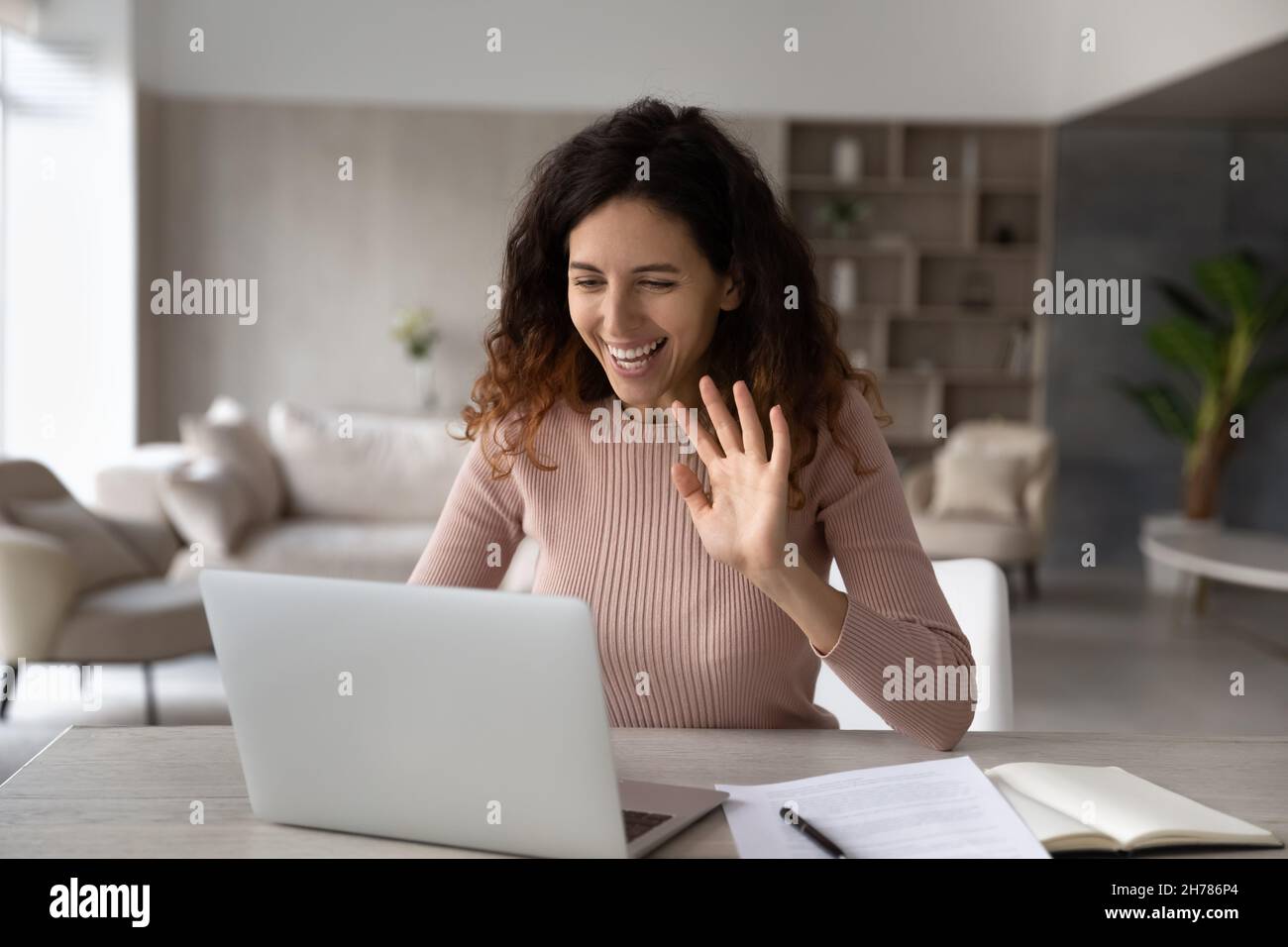 Lächelnd freundliche hispanische Geschäftsfrau winkt Hand an Laptop-Webcam Stockfoto