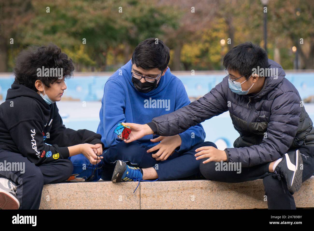 Ein junger Mann übergibt einen Rubik-Würfel an einen Freund. Im Flushing Meadows Corona Park in Queens, New York. Stockfoto