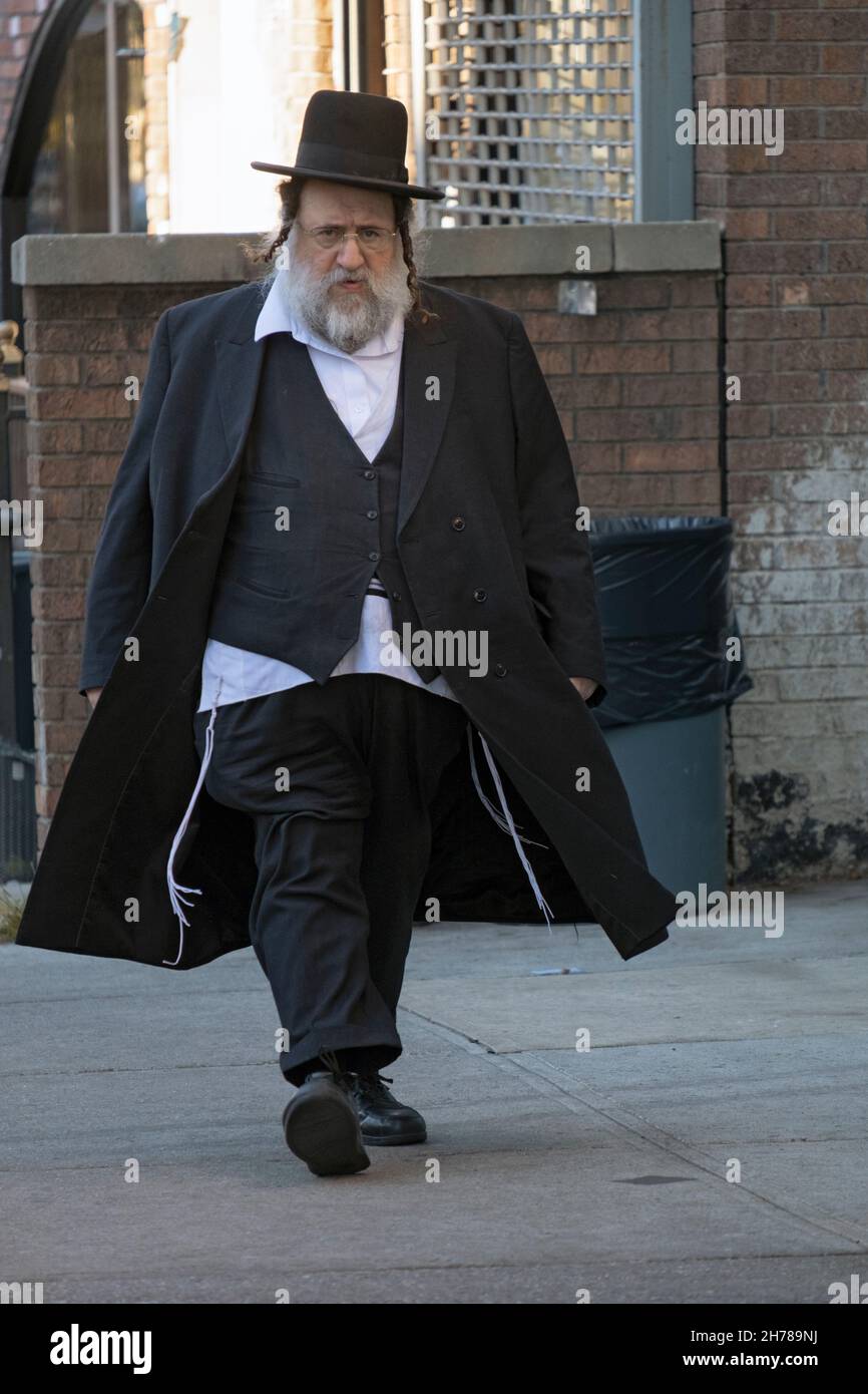 Ein orthodoxer jüdischer Mann mit langen Seitenschwellen geht schnell auf der Lee Avenue in Williamsburg, Brooklyn, New York City. Stockfoto