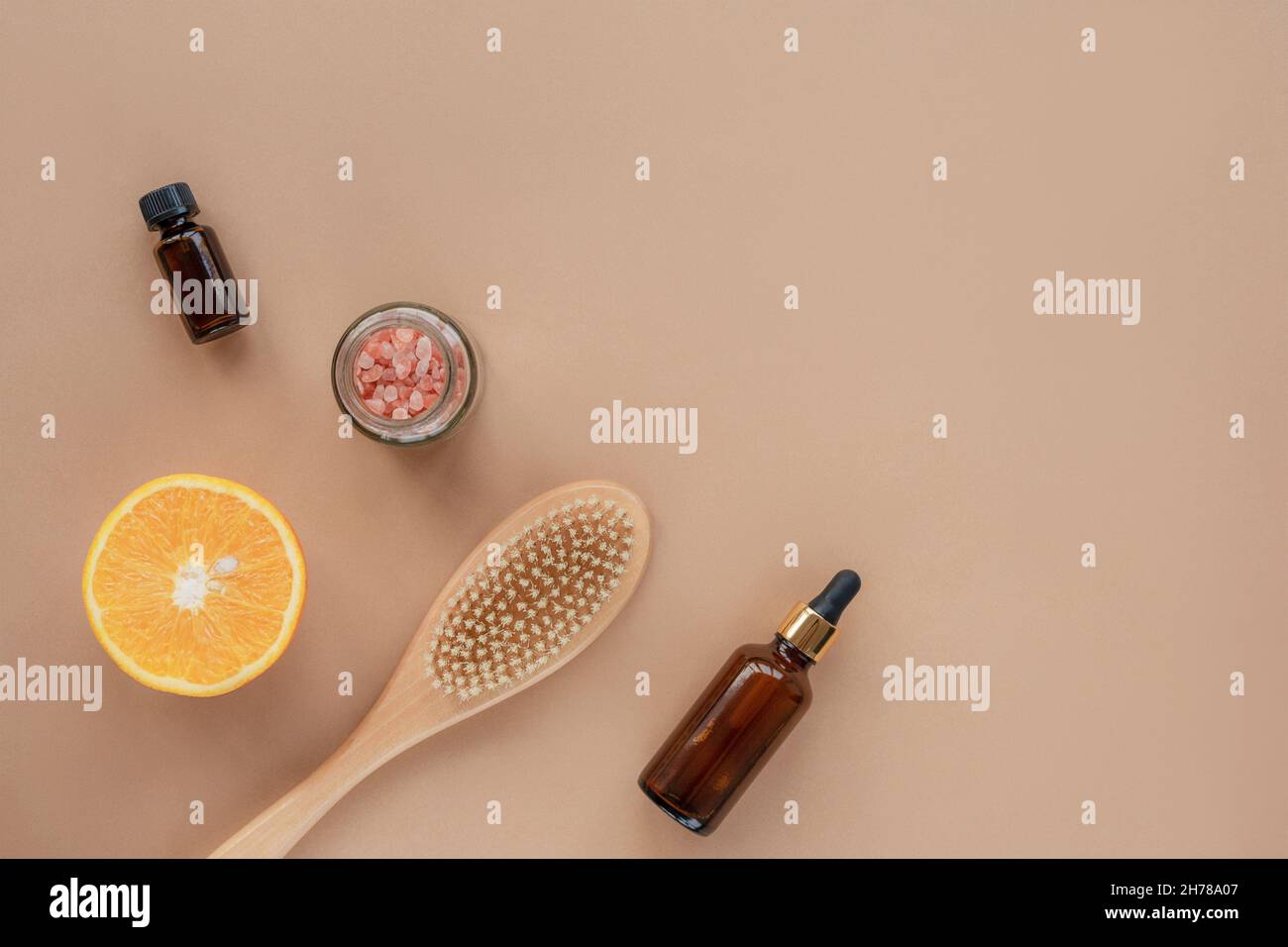 Natürliche Bio-Kosmetikprodukte, Öl, Serumflasche, Pinsel, himalaya-Rosa-Salz im Glas und orangefarbene Hälften auf beigem Hintergrund. Draufsicht, flaches Lay, c Stockfoto