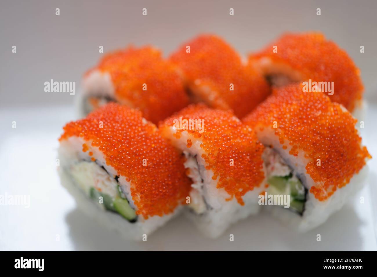 Sushi mit orange fliegendem Fischkaviar auf einem weißen Teller Stockfoto